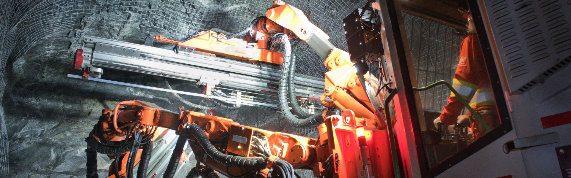 La bannière du site Web pour la page des services montre un employé de Redpath qui utilise une perceuse à percussion pour appliquer du treillis métallique sur les murs et le plafond d’un tunnel souterrain.